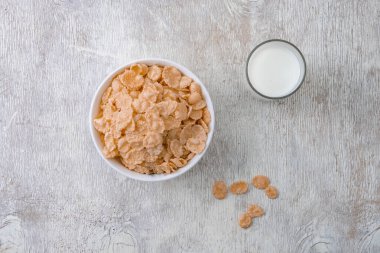 Bir kase mısır gevreği, sütlü, taze ahududu, yabanmersini. Sağlıklı kahvaltı için bir sürahi süt ve beyaz tahta üzerinde bir bardak.