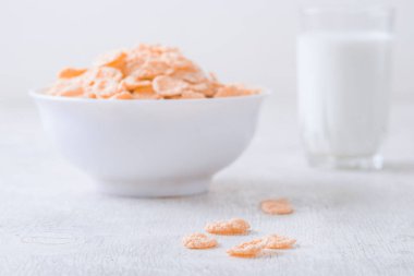 Bir kase mısır gevreği, sütlü, taze ahududu, yabanmersini. Sağlıklı kahvaltı için bir sürahi süt ve beyaz tahta üzerinde bir bardak.