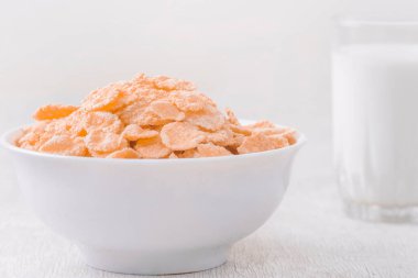 Bir kase mısır gevreği, sütlü, taze ahududu, yabanmersini. Sağlıklı kahvaltı için bir sürahi süt ve beyaz tahta üzerinde bir bardak.