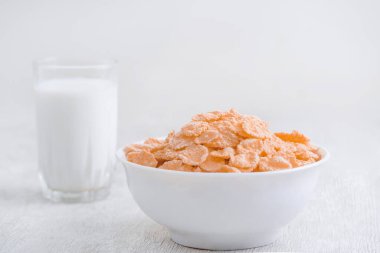 Bir kase mısır gevreği, sütlü, taze ahududu, yabanmersini. Sağlıklı kahvaltı için bir sürahi süt ve beyaz tahta üzerinde bir bardak.