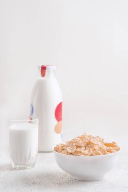 Bir kase mısır gevreği, sütlü, taze ahududu, yabanmersini. Sağlıklı kahvaltı için bir sürahi süt ve beyaz tahta üzerinde bir bardak.