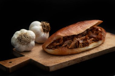 Shawarma ve sarımsak ahşap masada, siyah arka planda.
