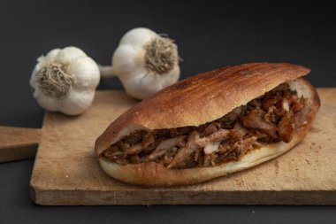 Shawarma ve sarımsak ahşap masada, siyah arka planda.