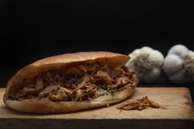 Shawarma ve sarımsak ahşap masada, siyah arka planda.