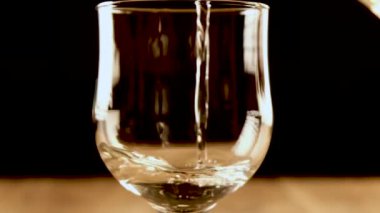 Beyaz şarabı bardağa dolduran kişi, yakın çekim, yavaş çekim.