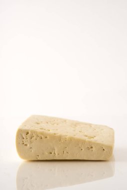 Beyaz arka planda izole edilmiş bir peynir parçası.