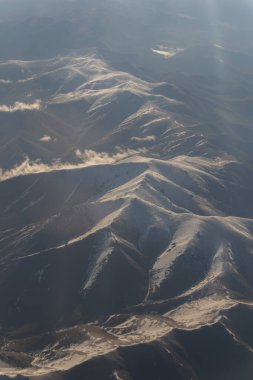 Bulutların ve dağların havadan görünüşü. Uçak penceresinden görüntüle.