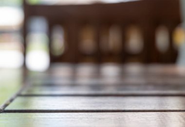 Ahşap masa ve kafenin arka planında Bokeh 'li sandalyeler.