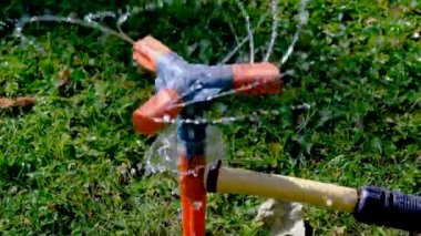 Yeşil çimen arka planında otomatik sulama kutusu olan su hortumu. Bahçedeki su bidonu .