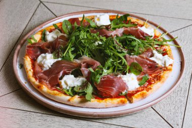 Prosciutto, roka ve peynirli pizza.