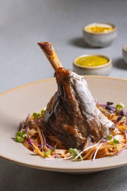 Lamb chop with noodles, sauce and mustard on a gray background