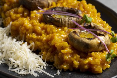 Pumpkin risotto with mushrooms and parmesan cheese on black plate