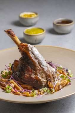 Lamb chop with noodles, sauce and mustard on a gray background