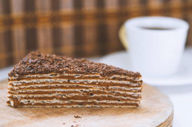 Tahta tabakta bir parça çikolatalı kek ve bir fincan kahve.