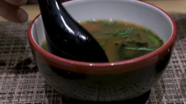 Adam restoranda Miso çorbası içiyor. 