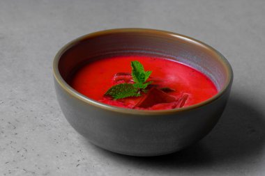 Cold beetroot soup with mint in a bowl on a gray background