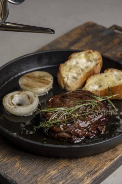 Tost ve biberiyeli kızarmış biftek, zeytinyağı serpiştirilmiş.