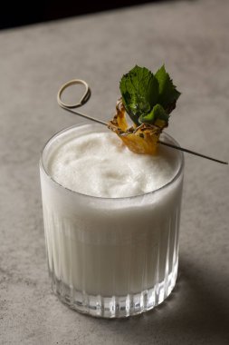 Gri arka planda ananas ve nane aromalı Pina colada kokteyli.