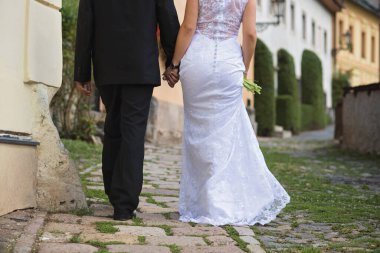 the bride and groom walking along the historic street of the city