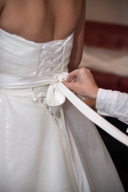 tying the wedding dress of the young bride before the ceremony