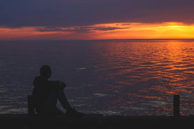 Kobuleti 'deki Karadeniz kıyısında gün batımını seyreden bir adamın silueti.