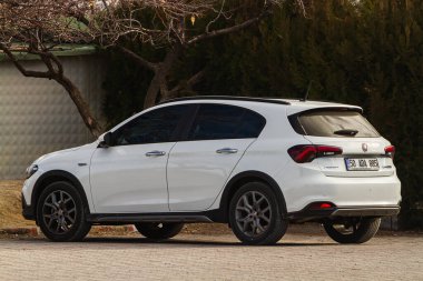 Side, Turkey -January 21, 2023:  white Fiat Egea Cross   is parked  on the street on a warm summer day against the backdrop of a buildung, trees