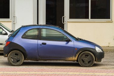 Side, Turkey -January 21, 2023:     blue Ford Ka  is parked  on the street on a warm day against the backdrop of a fence, garden