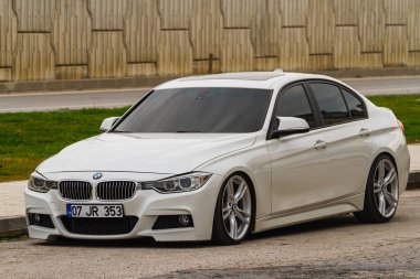 Kenar, Türkiye - 21 Ocak 2023: Beyaz BMW 3 serisi şehrin arka planına karşı caddede park halinde. 