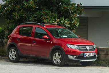 Side, Turkey -January 21, 2023:     red Dacia Sandero Stepway  is parked  on the street on a warm summer day against the  garden