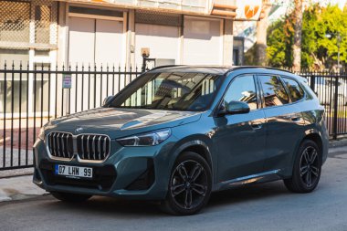  Side, Turkey -January 21, 2023:   blue  BMW X-1  is parked  on the street in city against the backdrop of a buildung, garden 