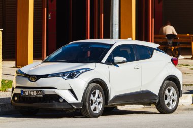 Side, Turkey -January 23, 2023:  white  Toyota Ch-r  is parked  on the street on a warm  day against the backdrop of a buildung, trees, shops