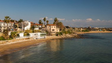 Türkiye 'de deniz kıyısında yeşil bitkilerle dolu eski taş antik evler, kafe. Tarafı Türkiye 'de daha popüler bir turizm beldesi.