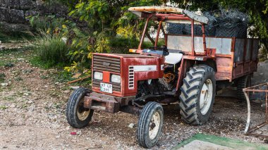 Side, Turkey  january 27 2023:        Old red  Tractor   is parked  on the street on a warm summer day against the backdrop of a  park  