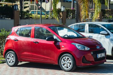 Yana, Türkiye - 23 Ocak 2023: Kırmızı Hyundai i10 bir yaz günü bir dükkanın arka planına karşı sokağa park ediyor 