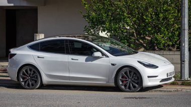 Yana, Türkiye - 05 Şubat 2023: Beyaz Tesla Model 3 sıcak bir günde sokağa park edildi  