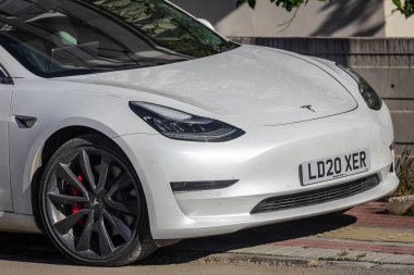 Yana, Türkiye - 05 Şubat 2023: Beyaz Tesla Model 3 sıcak bir günde sokağa park edildi  