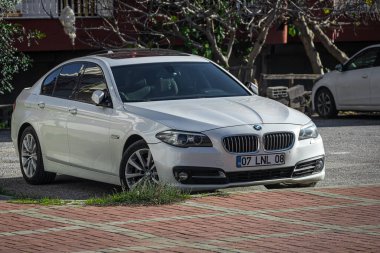 Yana, Türkiye - 05 Şubat 2023: Beyaz BMW 320, şehrin caddesinde park edilmiş bir evin arka planına karşı.  