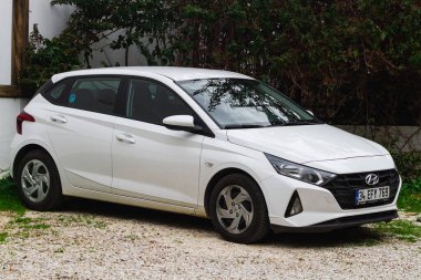 Yan, Türkiye 05 Şubat 2023: Beyaz Hyundai i20 bir yaz gününde sokağa park ediyor  