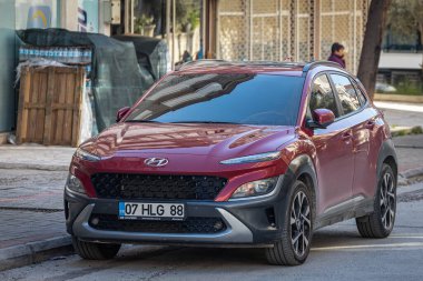Taraf; Türkiye 09 Şubat 2023: Kırmızı Hyundai Kona, sıcak bir yaz gününde bir binanın arka planına park etti. 