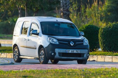Yana, Türkiye - 23 Ocak 2023: Beyaz Renault Kangoo sıcak bir yaz gününde palmiyelerin arkasına doğru hızla sürüyor