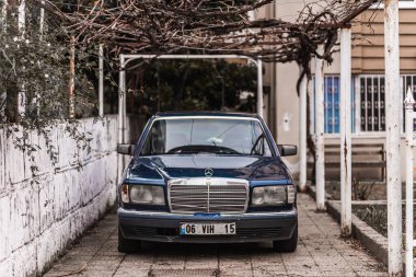Yan, Türkiye 9 Şubat 2023: Siyah Mercedes-Benz W124, sıcak bir günde bir binanın zeminine karşı sokağa park edilmiştir. Türkiye 'de sokakta klasik bir arabanın fotoğrafı 
