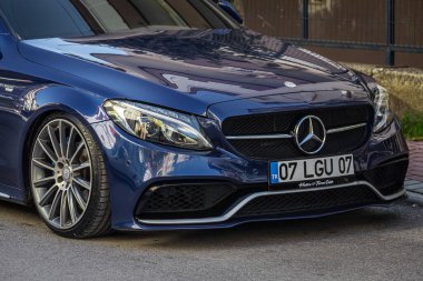 Yan, Türkiye 05 Şubat 2023: Mavi Mercedes-Benz C sınıfı sıcak bir günde bir bahçe zeminine karşı sokağa park edildi  