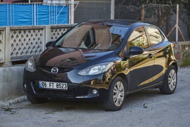Yana, Türkiye - 11 Şubat 2023: Siyah Mazda 2 sıcak bir yaz gününde parka karşı sokağa park ediyor