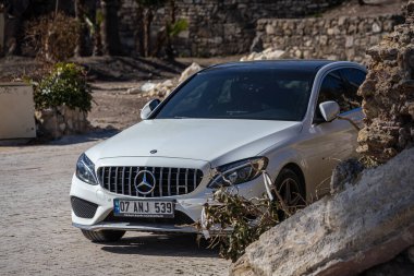 ; Türkiye 09 Şubat 2023: Beyaz Mercedes-Benz C sınıfı eski şehrin arka planına karşı sıcak bir günde sokağa park edildi 