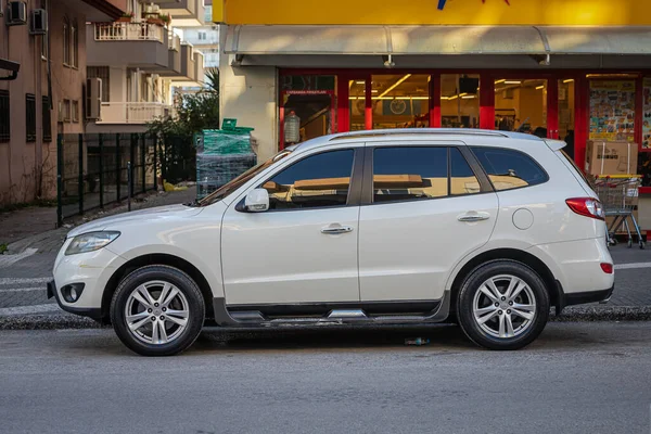 stock image Side, Turkey - February 13, 2023:  white  Hyundai Santa Fe   is parked  on the street on a warm summer day against the  building, fence