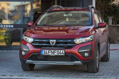 Yana, Türkiye - 13 Şubat 2023: Kırmızı Dacia Sandero Stepway sıcak bir yaz gününde bahçeye park etti