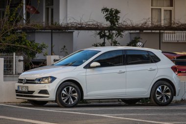 Yan, Türkiye 13 Şubat 2023: Beyaz Volkswagen Polo, sıcak bir günde sokakta park halinde. 