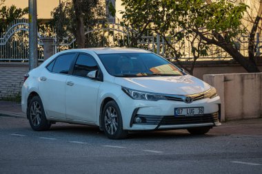 Yan, Türkiye 13 Şubat 2023: Beyaz Toyota Corolla sıcak bir günde sokağa park etti  