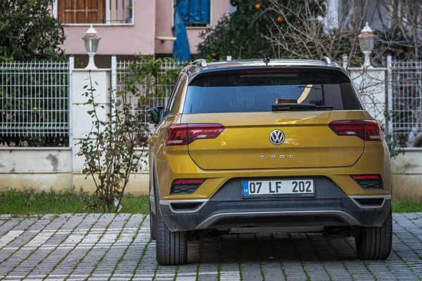 Yana, Türkiye - 13 Şubat 2023: Sarı Volkswagen T-Roc sıcak bir günde bir inşaat tezgahına, dükkanlara karşı sokağa park edildi