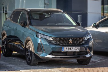 ; 18 Şubat 2023: Mavi yeni Peugeot 3008, sıcak bir günde bir otosalonun arka planına karşı sokağa park edildi  